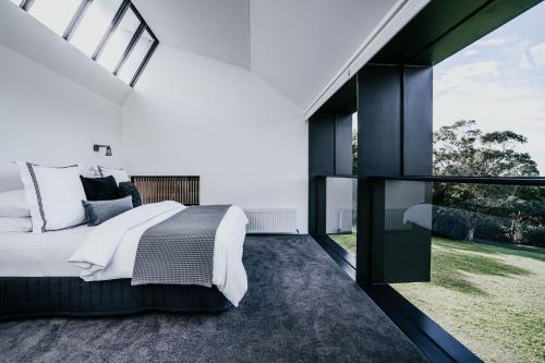 a bedroom with a large bed and a large window at Alkina Lodge Milu in Wattle Hill