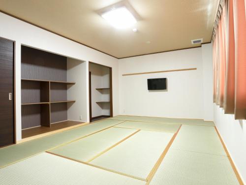 an empty room with a door and a room with shelves at Onsenminshuku Kosakaya in Nachikatsuura