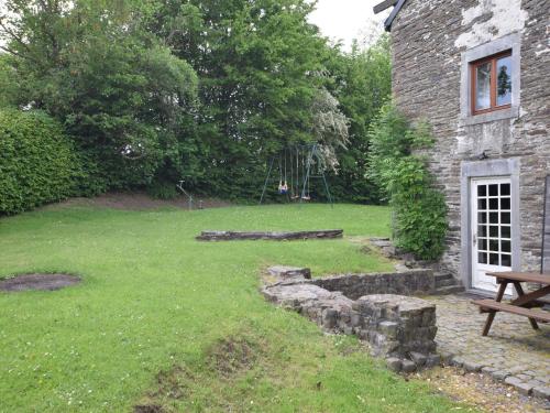 a yard with a bench and a stone building at Spacious Stay, Tenneville in Tenneville