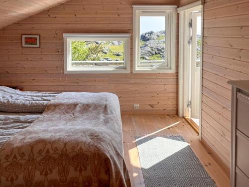 a bedroom with wooden walls and two windows at Traditional Cabin With Sea View In Jæren in Sirevåg
