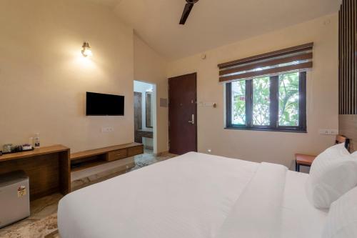 a bedroom with a large white bed and a television at Palette - Coastal Grand Hotels & Resorts, OMR in Chennai
