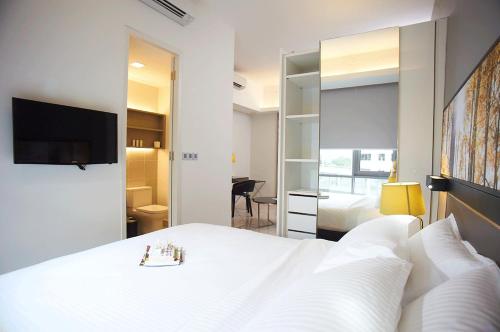 a bedroom with a large white bed and a mirror at The Signature Hotel & Serviced Suites Kuala Lumpur in Kuala Lumpur