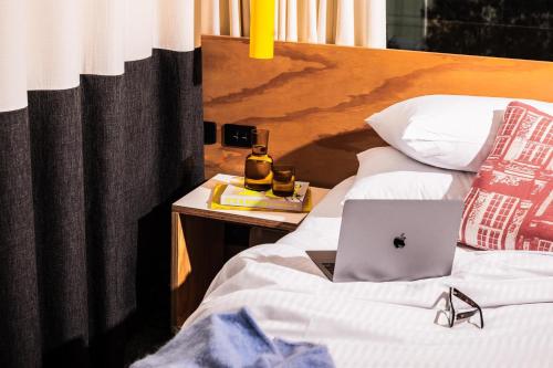 a bed with a laptop sitting on top of it at Atura Adelaide Airport in Adelaide
