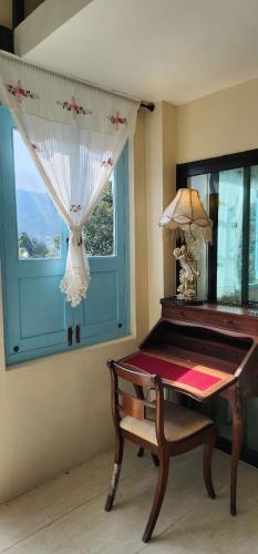 a table in a room with a window and a table with a lamp at Flora Prairie at Mae Rim, Chiang Mai in Ban Tai