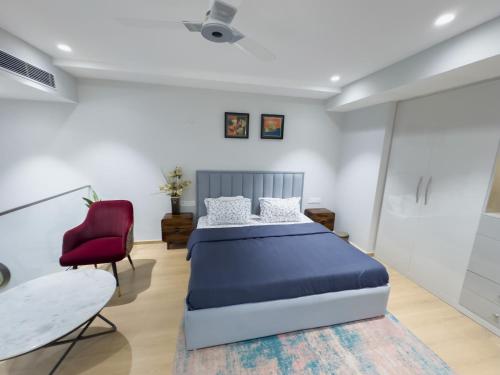 グルガオンにあるKiki Stay - Loft Studio Apartmentのベッドと赤い椅子のある寝室