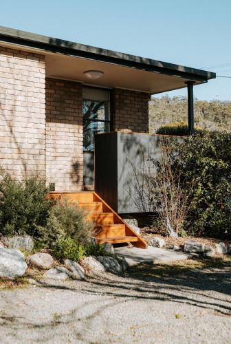 a brick house with wooden stairs in front of it at Kooringal - Your Home by the Ocean in Bicheno in Bicheno