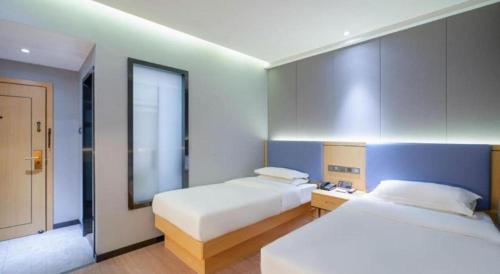a hotel room with two beds and a window at Green Tree Inn Urumqi San'gong Metro Station Exit in Ürümqi