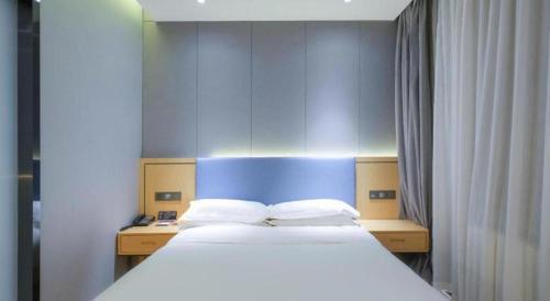 a bedroom with a large bed with a blue headboard at Green Tree Inn Urumqi San'gong Metro Station Exit in Ürümqi