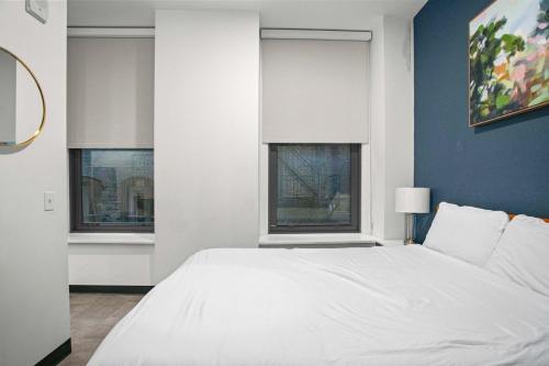 un letto bianco in una stanza con due finestre di CozySuites Stunning 1BR in Downtown Pitts 37 a Pittsburgh