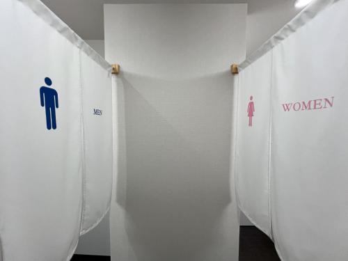 a hallway with white walls with men and women signs at おおさか城北 宿福 in Osaka