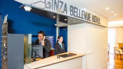 two people standing at a counter in a office at Ginza Bellevue Hotel in Tokyo