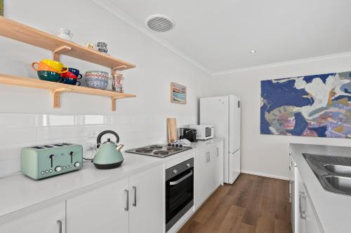 a white kitchen with a stove and a refrigerator at The Shack at Maslin Beach - C21 SouthCoast Holidays in Maslin Beach