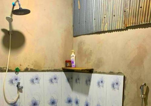 a bathroom with a shower with blue flowers on the wall at Family Batcave Homestay in Battambang