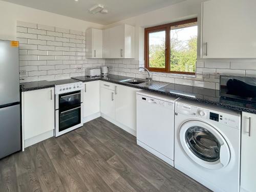 Una cocina con gabinetes blancos y lavadora y secadora. en Cassia Lodge, en Burnham-on-Sea