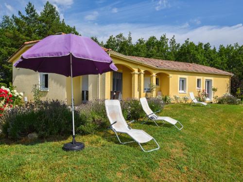 two chairs and an umbrella in front of a house at Villa in Cazals with pool in Cazals