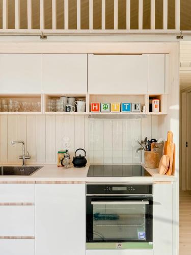 a kitchen with white cabinets and a stove top oven at Island Paradise Family-Friendly Near The Sea in Ljugarn