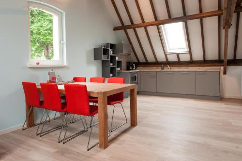 una cucina con un tavolo di legno e sedie rosse di Ruyge Weyde Logies, Eco Farm a Oudewater