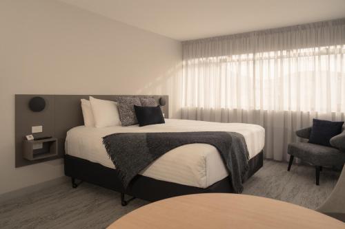 a bedroom with a large bed and a chair at 429 Apartments & Suites in Hobart