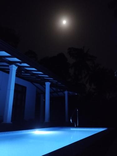 a nightime view of a swimming pool with a moon at Serene Bliss Villa in Unawatuna