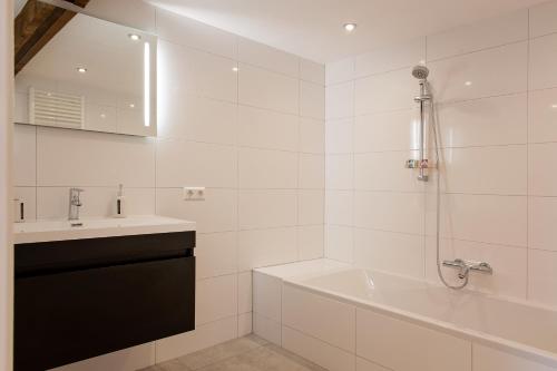 ein weißes Badezimmer mit einem Waschbecken, einer Badewanne und einem Waschbecken in der Unterkunft Ruyge Weyde Logies, Eco Farm in Oudewater