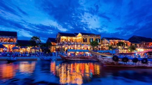 a group of buildings on the water at night at Hoi An Royal Beachfront Villas in Dien Ban