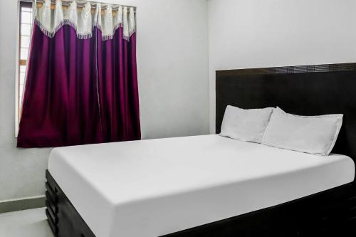 a bed in a room with a red curtain at Hotel O Raj Vihar in Mohammadnagar