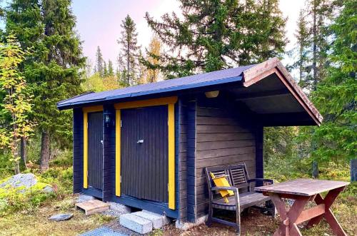 una tettoia con un tavolo, una sedia e un tavolo da picnic di Forest Cabin Near Trillevallen Ski Resort a Trillevallen