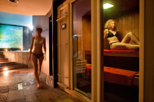a woman walking through a room with two beds at Ostia Antica Park Hotel & Spa in Ostia Antica
