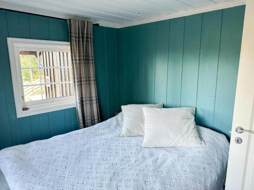 a bedroom with blue walls and a bed with two pillows at Family Cabin With Charm in Mesnali