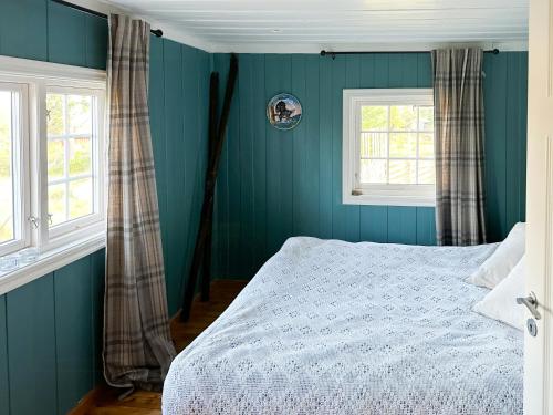 a blue bedroom with a bed and two windows at Family Cabin With Charm in Mesnali