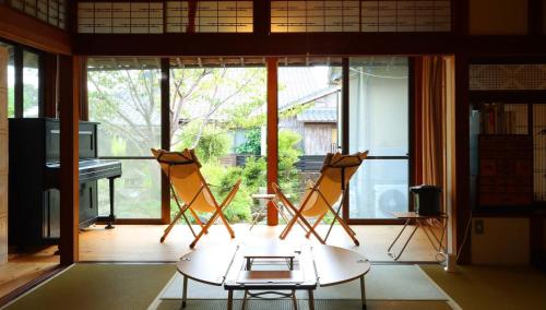 a room with two chairs and a table and a piano at ゲストハウスKoToKoTo in Makurazaki
