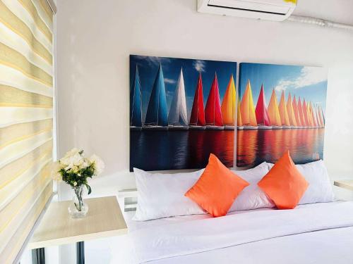 a bed with orange pillows and a painting of sailboats at OYO 1157 Kegama Residences 1 in Cavite