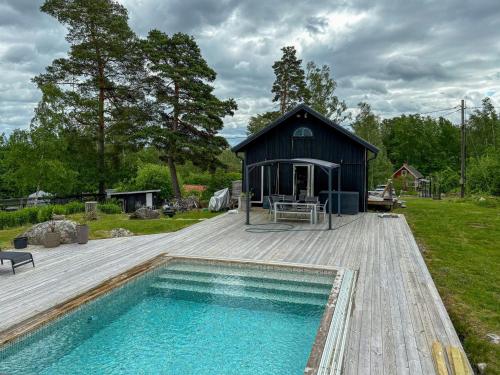 a small black building with a swimming pool on a deck at Summer House With Pool On Hilltop In Ostra Knall in Eskilstuna