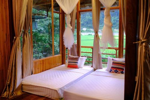 two beds in a room with a window at Chải Eco Home in Mù Cang Chải