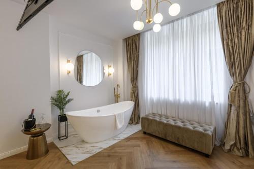 a bathroom with a large tub and a large window at Eden Central Boutique Suites - Garden & Spacious Apartments in Cluj-Napoca