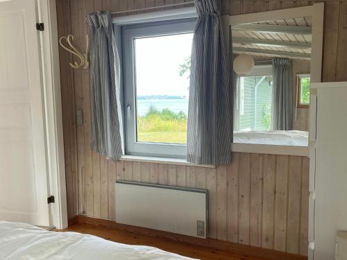 a bedroom with a window and a bed and a mirror at Holiday Home With Panoramic View Of Kalø Bay in Knebel