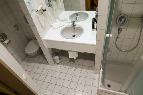 a bathroom with a sink and a shower and a toilet at Hotel am Südtor in Backnang