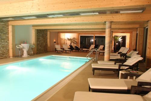 a pool in a hotel room with chairs and tables at Landhaus Ramsau in Ramsau am Dachstein
