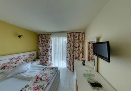 a hotel room with a bed and a flat screen tv at Pensiunea Cabana Soimul in Comăneşti