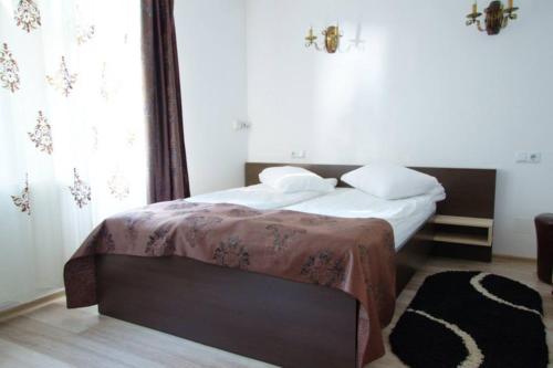 a bedroom with a bed with white sheets and pillows at Pensiunea Cabana Soimul in Comăneşti