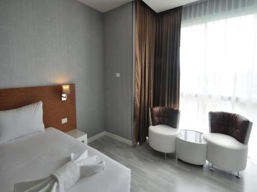 a hotel room with a bed and two chairs at Tanzeno Hotel in Nong Khai