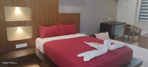 a bedroom with a large red bed with two white towels at HOTEL AL AMANA TOWER in Kondotti