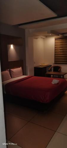 a bedroom with a red bed and a table at HOTEL AL AMANA TOWER in Kondotti