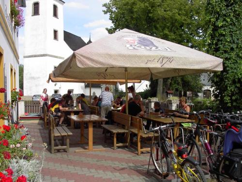 a group of people sitting at tables under an umbrella at Pension a restaurace Rudolec in Český Rudolec