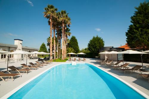 uma grande piscina com cadeiras e guarda-sóis em Hotel La Palma de Llanes em Llanes