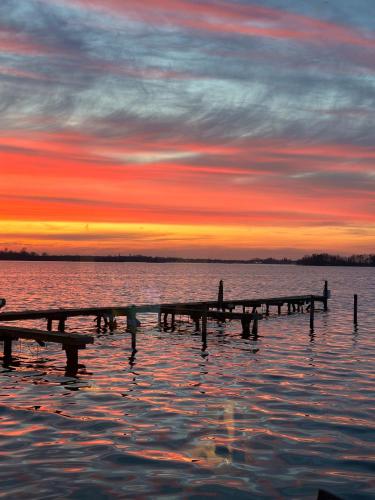 a dock in the water with a sunset in the background at woonboot de dobber loosdrechtse plassen 4-8 personen in Loosdrecht