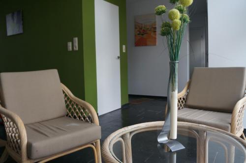 two chairs and a vase with flowers on a glass table at Gîte de L´ô d´Or in Villers-devant-Orval