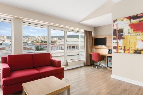 ein Wohnzimmer mit einem roten Sofa und großen Fenstern in der Unterkunft Ramada Encore Istanbul Kartal in Istanbul