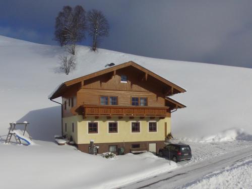 dom na śniegu z samochodem zaparkowanym przed budynkiem w obiekcie Apartment in Wagrain with Stunning Mountain Views w mieście Wagrain