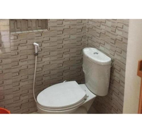 a white toilet in a bathroom with a brick wall at OYO 1157 Kegama Residences 1 in Cavite
